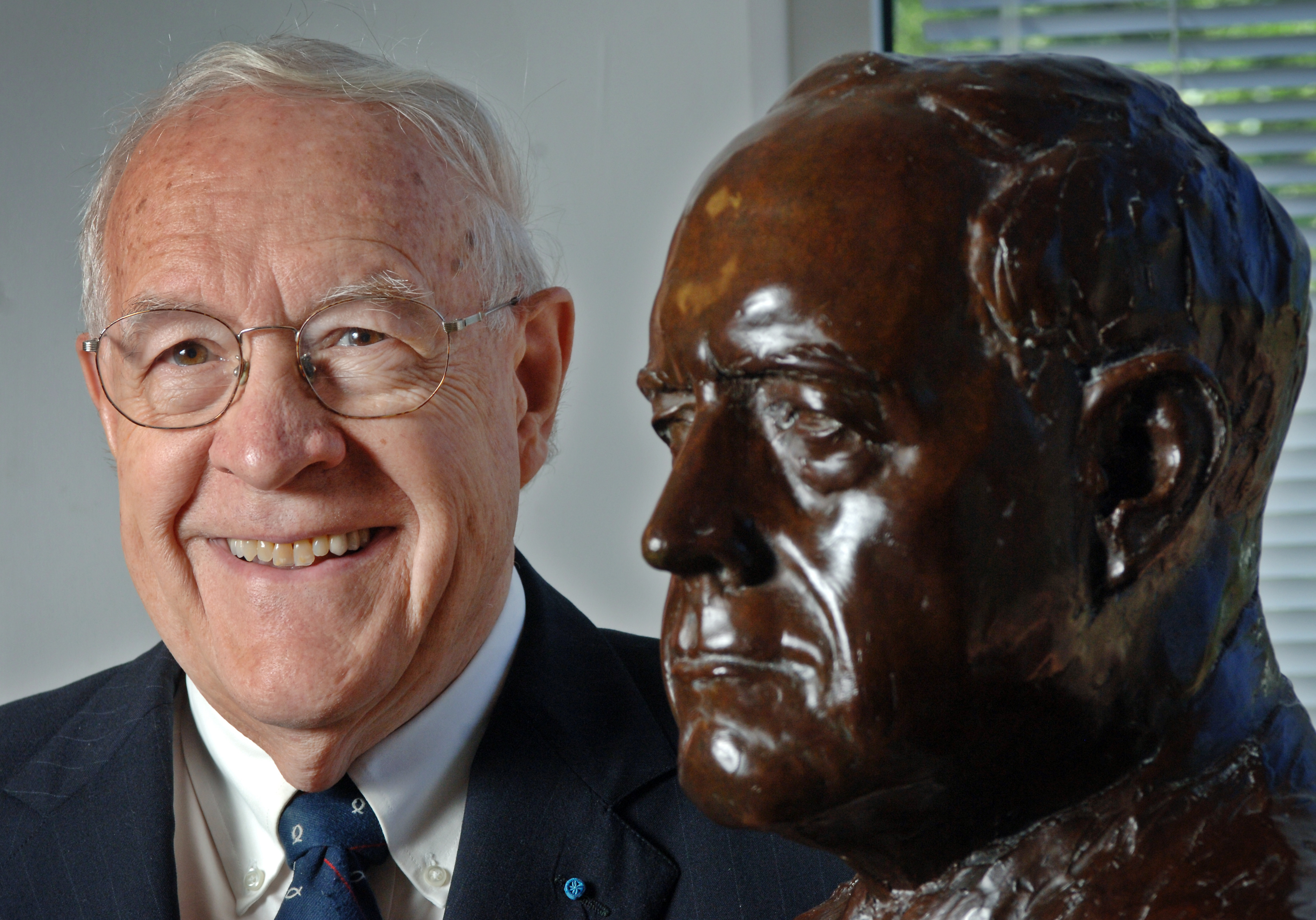 Fred Brooks poses with a bust made in his honor in Sitterson Hall. (photo by Dan Sears)