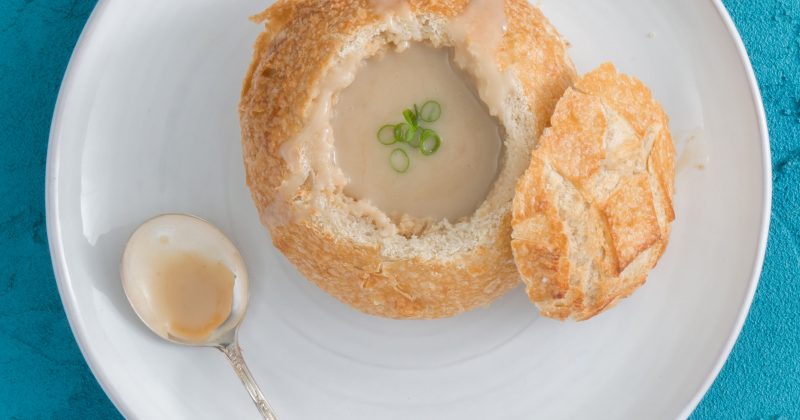 A bread bowl of soup on a plate
