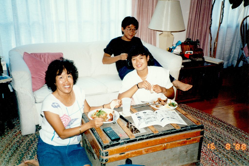Older photo of Jennifer Ho in high school with her mother and Uncle Frank eating food