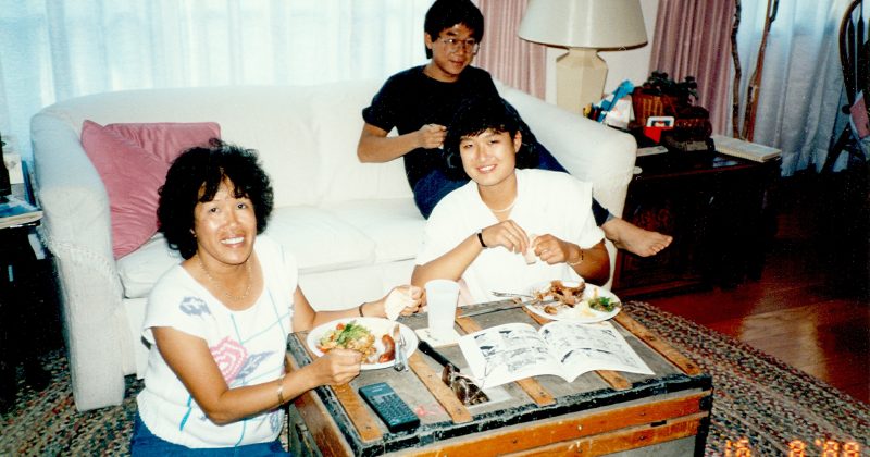 Older photo of Jennifer Ho in high school with her mother and Uncle Frank eating food