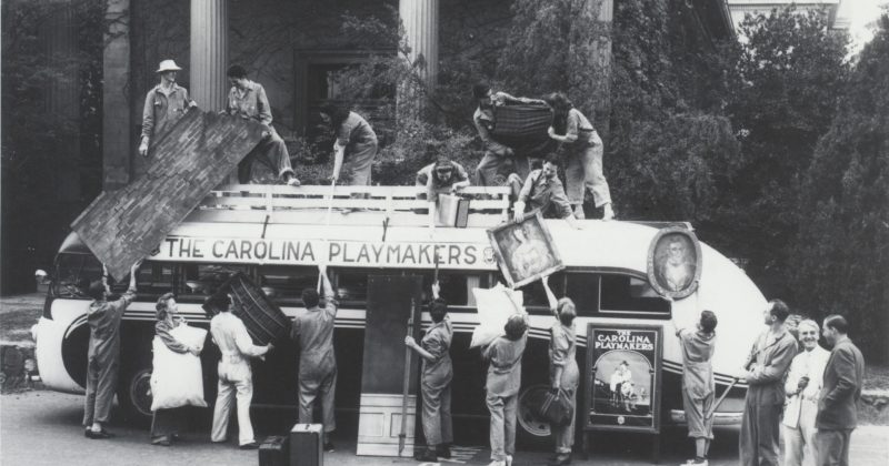 Members of the Carolina Playmakers load up a large bus with props and set pieces.