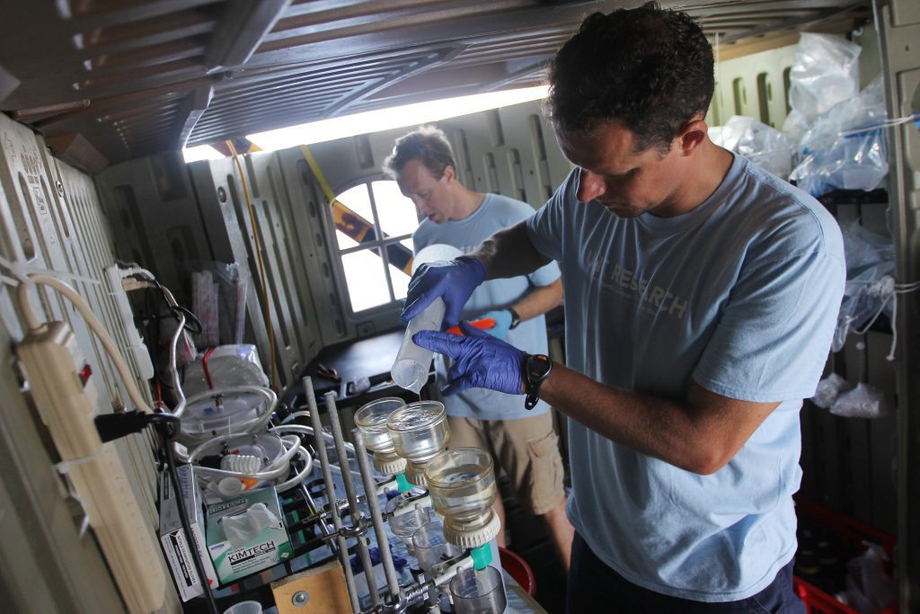Adrian Marchetti (foreground) and Scott Gifford run water samples in their makeshift lab aboard the Sierra Negra, a research vessel owned by the Galapagos National Park. (Photo by Mary Lide Parker)