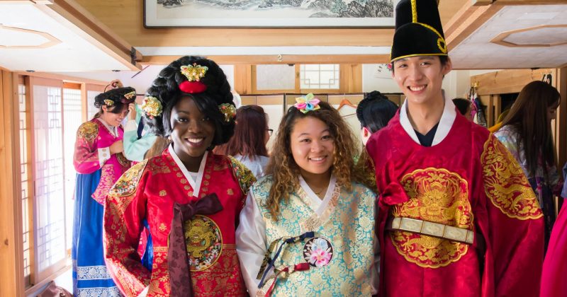 Phillips Ambassador Ntiense Inyang poses with two students, all wearing tradition South Korean clothing