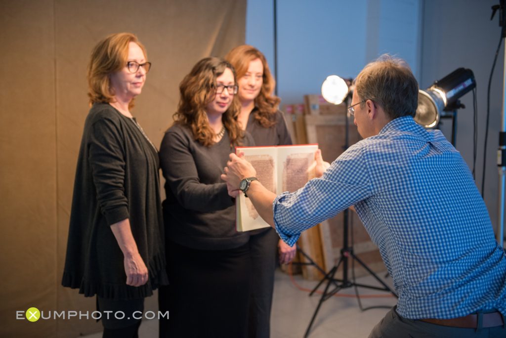 Steve Exum arranges a book held by Glaire Anderson, as Jan Chambers and Laura Miller stands behind her, ready for a photo shoot.