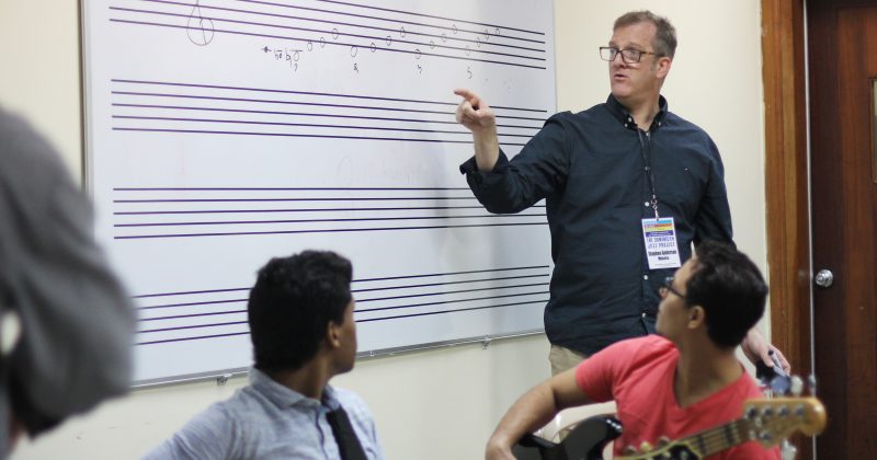 Steve Anderson stands at a whiteboard and explains some of the theory behind improvisation in jazz composition at the National Conservatory of Music in Santo Domingo.