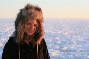 Zena Cardman poses in front of the barren, frigid landscape of Antarctica. 