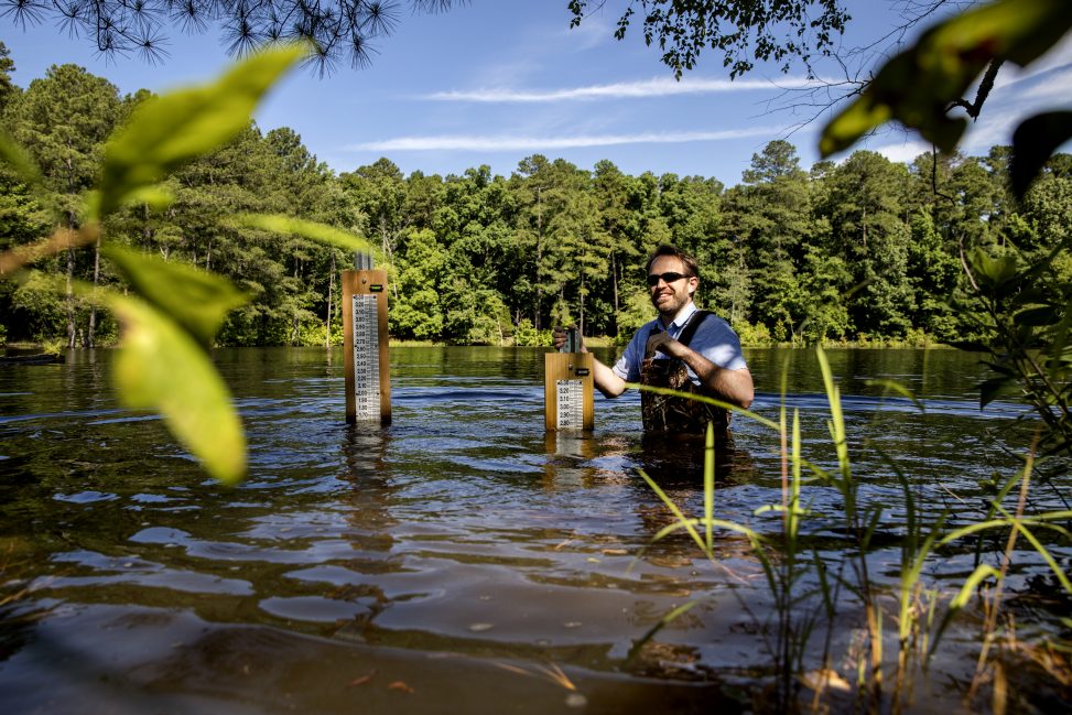 Tamlin Pavelsky, associate professor of geological sciences, measures water levels at Botany Pond in Chapel Hill as part of an ongoing water-storage project. (photo by Johnny Andrews)