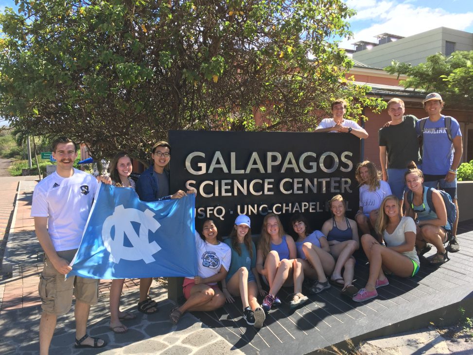Increasing private support for experiential learning opportunities, including study abroad, is a College campaign priority. (photo courtesy of Diego Riveros-Iregui). Students are shown here holding up a UNC banner and standing in front of a Galapagos Science Center sign from a study abroad trip to the Galapagos Islands.