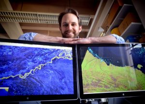 Tamlin Pavelsky with Landsat images of the Alaska coast and the Tanana River in his office in Mitchell Hall at the University of North Carolina at Chapel Hill. (photo by Dan Sears)