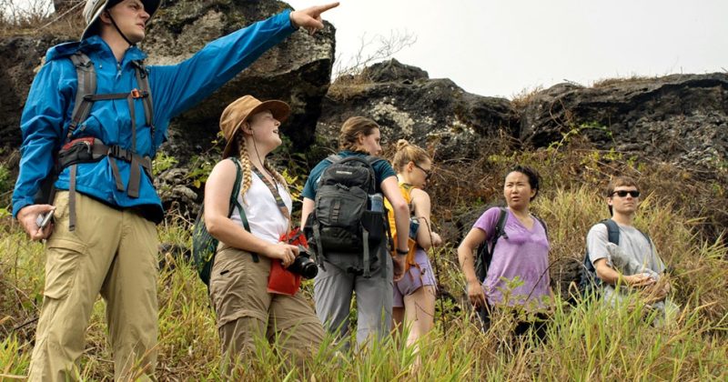 On one of the Galapagos Islands, a student points while other students look on.