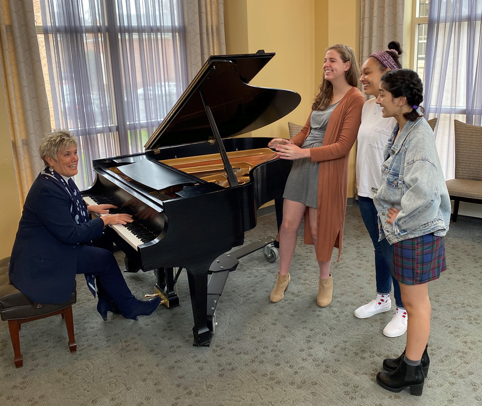 Terry Rhodes, at the piano, plays music with three students