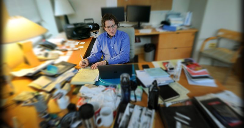 Adam Versényi works in his office, with a blurred effect around him.