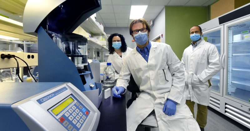 Samantha Pattenden, Paul Dayton and Sunny Kasoji wear lab coats and masks in the Triangle Biotechnology lab in Research Triangle Park.