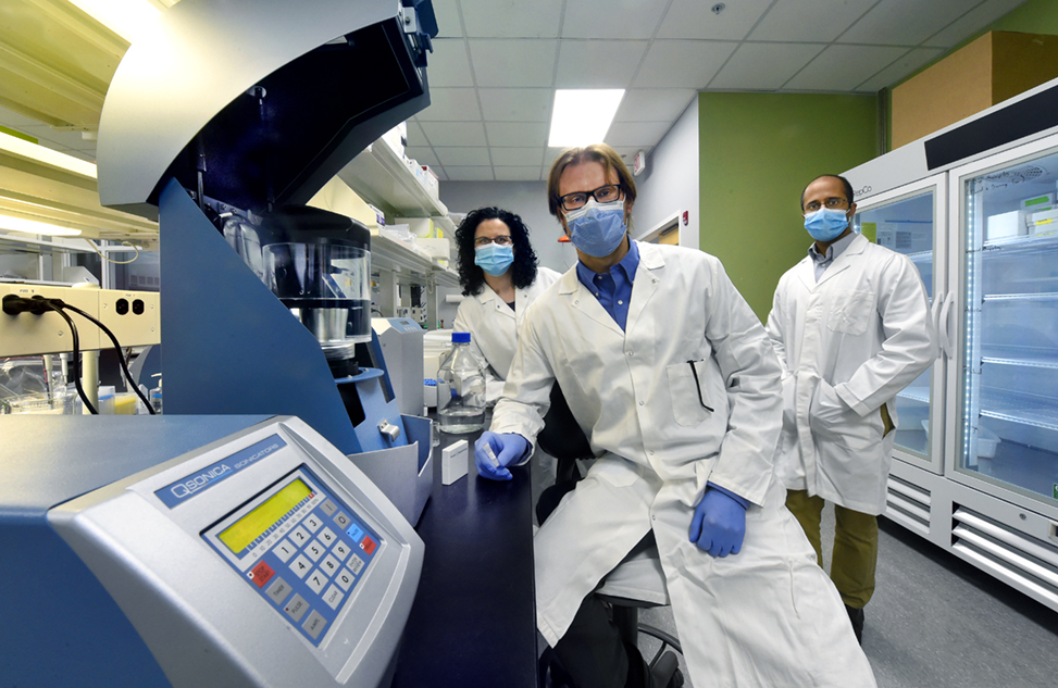 Samantha Pattenden, Paul Dayton and Sunny Kasoji wear lab coats and masks in the Triangle Biotechnology lab in Research Triangle Park.
