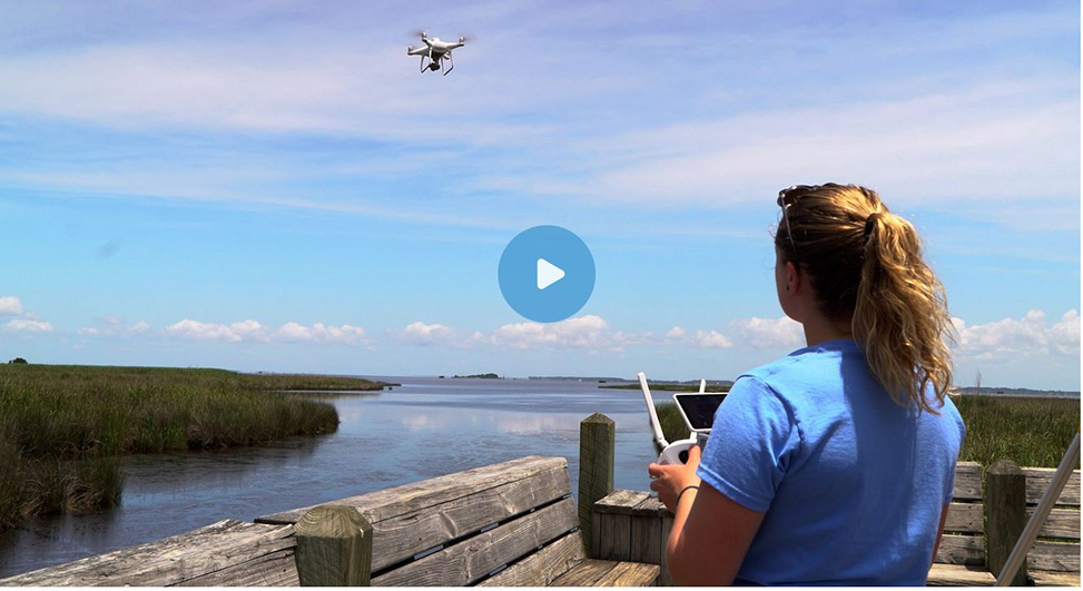 Photo of a female researcher flying a drone with her back to the camera.