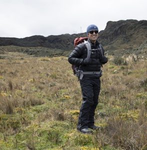 Diego Riveros-Iregui stands in the middle of the paramo wearing a backpack and warm weather gear.