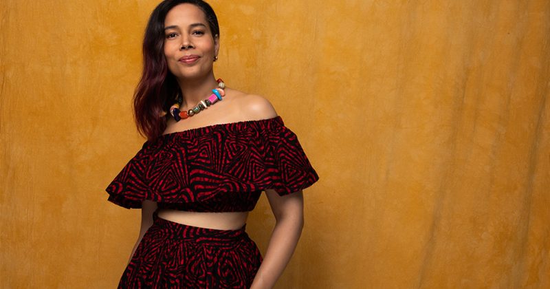 Rhiannon Giddens pictured smiling behind a yellow backdrop
