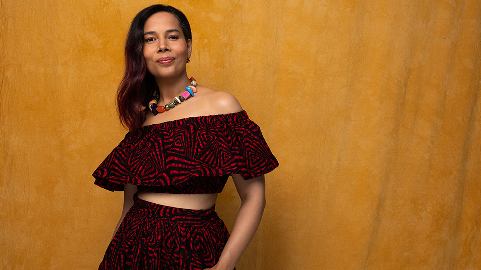 Rhiannon Giddens pictured smiling behind a yellow backdrop