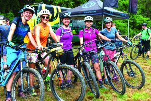 Bicyclists line up to ride the trails and smile at the camera.