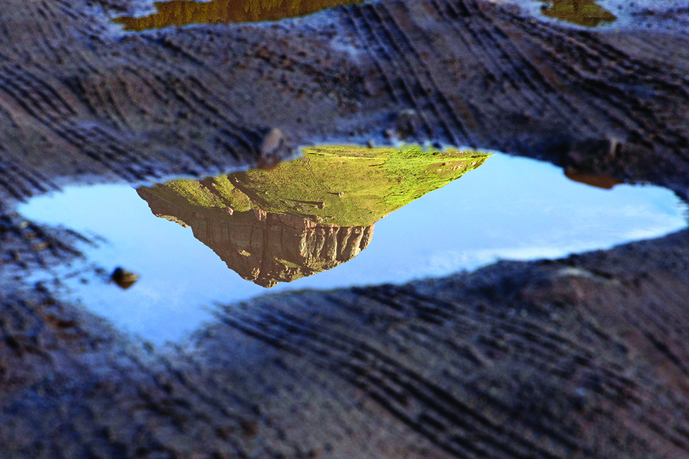 Closeup of a view of a mountaintop reflected in a pool of water.