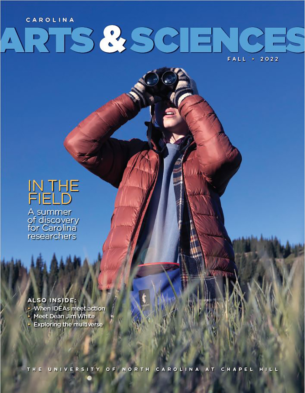 Cover of fall 2022 magazine shows a young woman researcher holding binoculars and looking up into the sky. She is standing in a field.