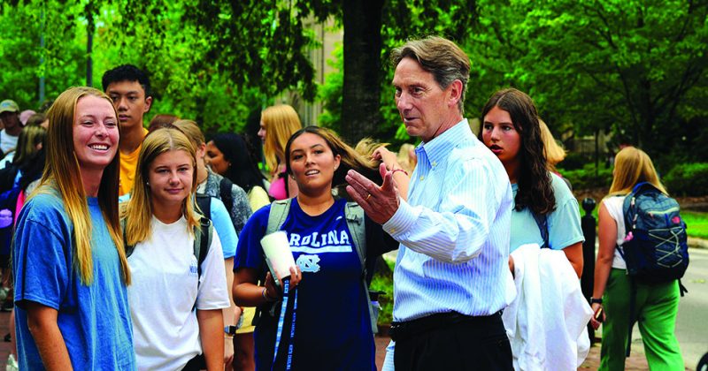 Dean White chats with students in line to take sips from the Old Well.