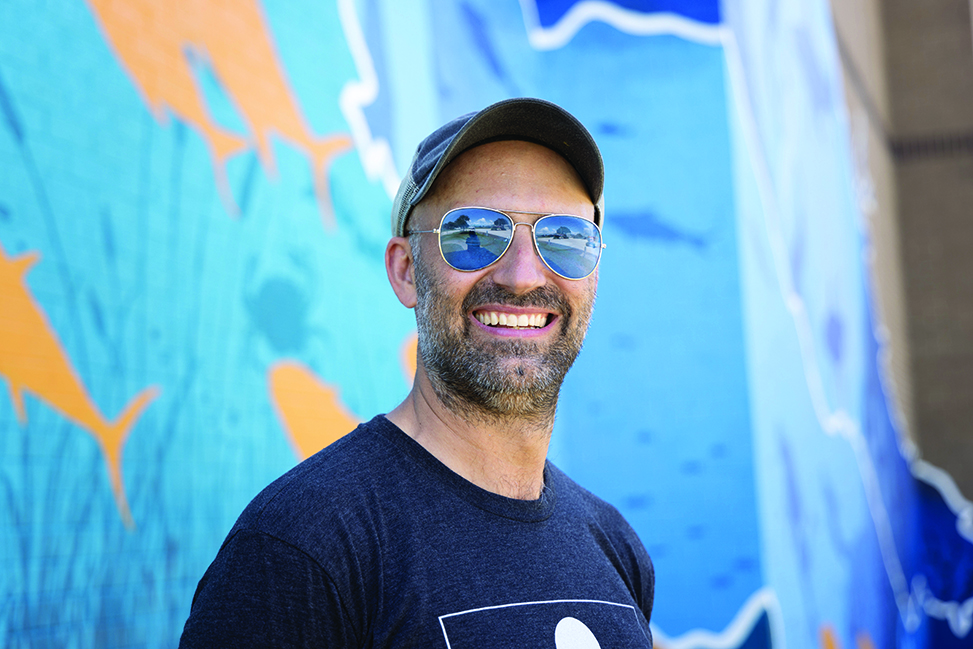 Muralist Max Dowdle smiles at the camera.