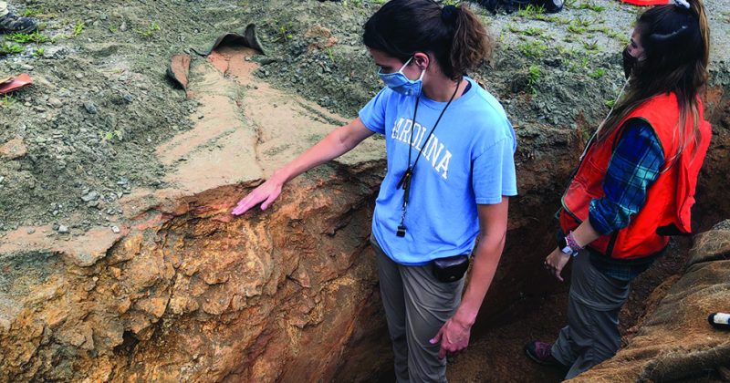 Two people stand in a fault line created by an earthquake