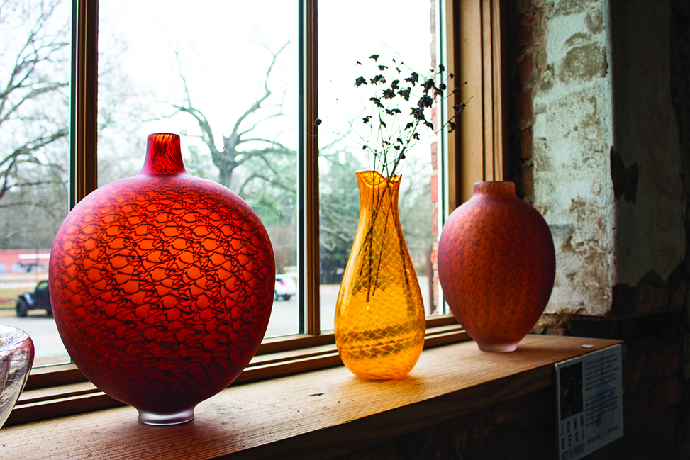 Three glass vases sit on a window shelf.