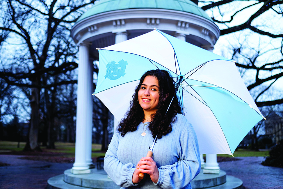 Dalal Azzam stands underneath an umbrella in front of the Old Well.