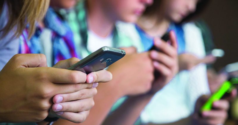 Teens text on their smartphones.