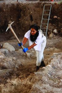Jada Enoch swings a pick-axe as she works at the Huqoq dig site.
